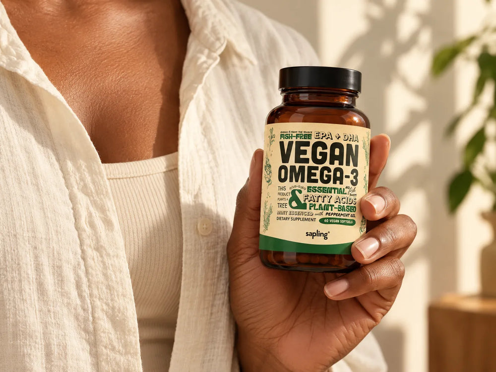 A hand holding a bottle of Sapling Vegan Omega-3 in sunlight
